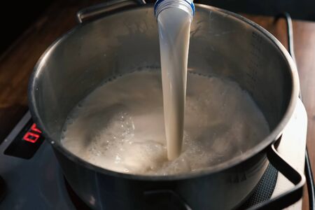 Pouring milk into the pan on the scales.の写真素材