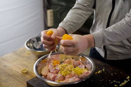 Squeezing lemons in a plate with chicken meat. lemon seasoning
