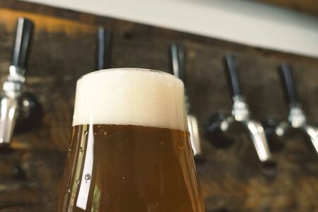 Pouring beer into a glass from the tap at the bar. Beer bottling.の写真素材