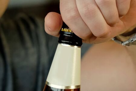 A man opens a bottle of beer, tasting beer.