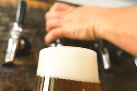 Pouring beer into a glass from the tap at the bar. Beer bottling.
