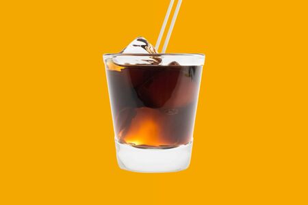 Glass with cola with ice and a straw on an orange background.の写真素材