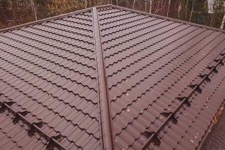Modern roof made of metal. Corrugated metal roof and metal roofing. House with a brown metal roof.の写真素材
