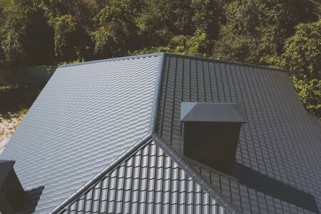 Modern roof made of metal. Gray-blue metal roof tiles on the roof of the house. Corrugated metal roof and metal roofing.の写真素材