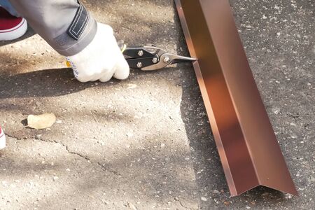 Worker shears a sheet of roofing metal. Scissors for metal.の写真素材