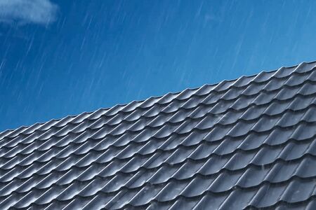 Rain pours on the metal roof tiles of the house. Rain on the roof. Modern roof made of metal. Corrugated metal roof and metal roofing.の写真素材