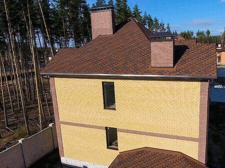 House with a roof from a bituminous tile. New brick house. Bituminous tile for a roof. a roof from a bituminous tile.の写真素材