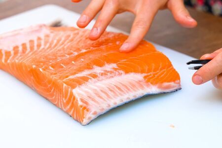Pulling tweezers of small bones from a piece of red fish.の写真素材
