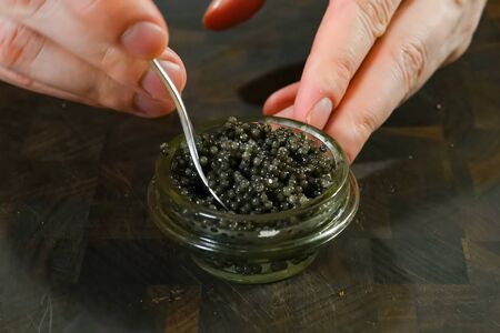 Stirring black caviar with a spoon in a glass jar.の写真素材