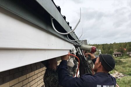 MOSCOW, Russia - August 29, 2019: Workers work to assemble the roof and drainage system.のeditorial素材