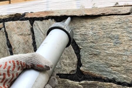 Singing the gaps between the wild stone on the cladding of the foundation. Facing the foundation of a houseの写真素材
