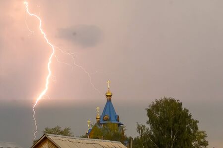 Lightning during a thunderstorm in the sky above the dome and cross of the church. Natural...