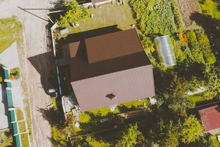 Modern roof made of metal. Brown metal tile on the roof of the house. Corrugated metal roof and metal roofing.の写真素材