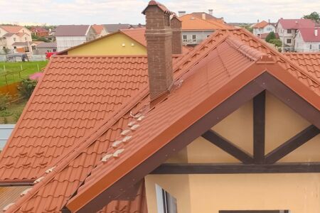 Modern roof made of metal. House with a new roof made of orange metal. View from above. Corrugated...