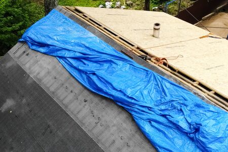 Worker does the installation of the roof of the house. Installation of metal tiles, snow retainers and other elements of the roof.の写真素材
