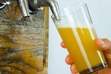 Pouring beer into a glass from the tap at the bar. Beer bottling.の写真素材