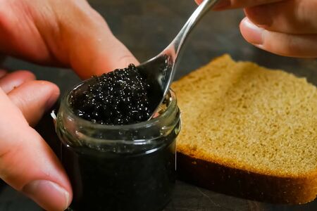 Stirring black caviar with a spoon in a glass jar.の写真素材