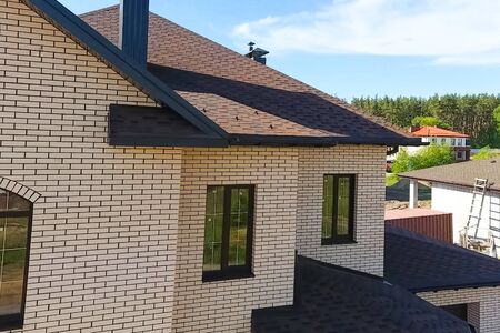 House with a roof from a bituminous tile. New brick house. Bituminous tile for a roof. a roof from a...