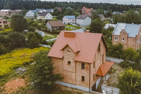 Modern roof made of metal. Corrugated metal roof and metal roofing. Beautiful pink brick brick house...