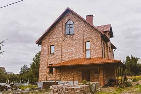 Modern roof made of metal. Corrugated metal roof and metal roofing. Beautiful pink brick brick house and orange roof.の写真素材