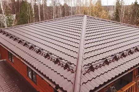 Modern roof made of metal. Corrugated metal roof and metal roofing. House with a brown metal roof.の写真素材