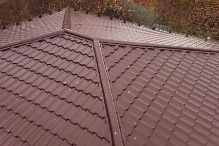 Modern roof made of metal. Corrugated metal roof and metal roofing. House with a brown metal roof.の写真素材