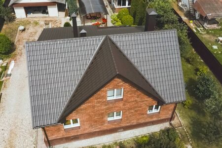 Modern roof made of metal. Corrugated metal roof and metal roofing. House with a brown metal roof.の写真素材