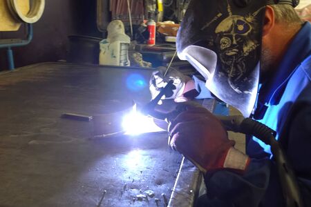 Moscow, Russia - June 3, 2018: Welder welds metal parts on a workbench.