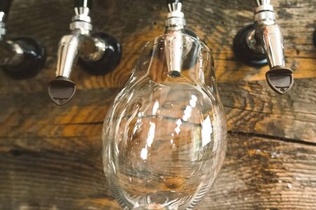 Pouring beer into a glass from the tap at the bar. Beer bottling.の写真素材