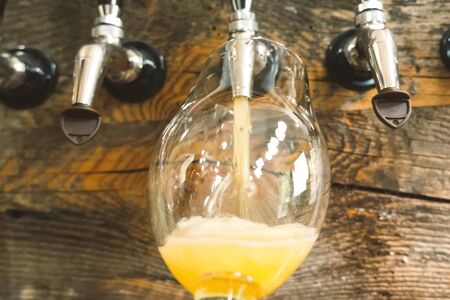 Pouring beer into a glass from the tap at the bar. Beer bottling.の写真素材