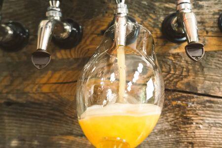 Pouring beer into a glass from the tap at the bar. Beer bottling.の写真素材