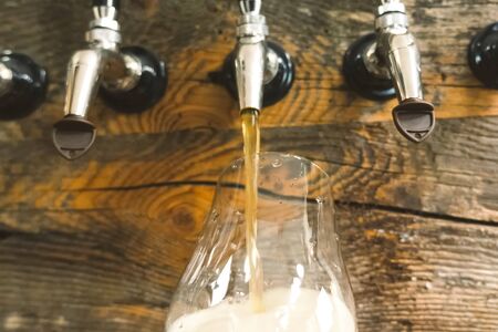 Pouring beer into a glass from the tap at the bar. Beer bottling.の写真素材