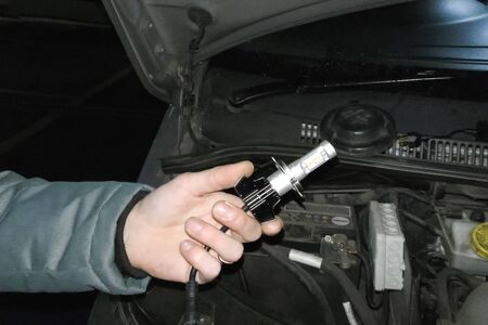 Xenon lamp in the hands of an electrician. Replacing xenon lamps.の写真素材