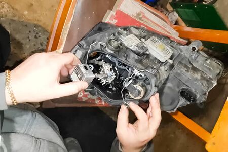 Xenon lamp in the hands of an electrician. Replacing xenon lamps.の写真素材