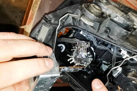 Xenon lamp in the hands of an electrician. Replacing xenon lamps.の写真素材