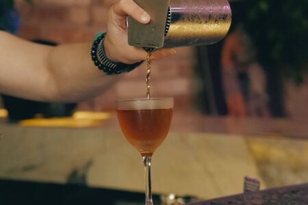 a Bartender pouring cocktail at bar counterの写真素材