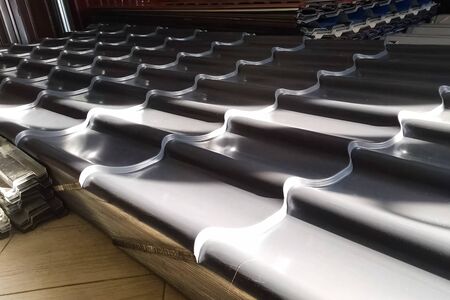 Sheets of metal in the warehouse of roofing building materials. Modern roof made of metal. Corrugated metal roof and metal roofing.の写真素材