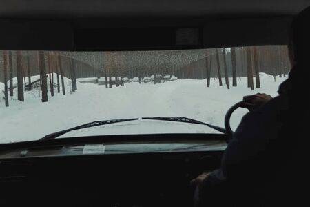 View from the interior of the car into the windshield, winter road through the forest in an SUV.の写真素材