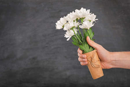 Teacher's day greeting card. Hand and flowers on black chalkboard background. Copy space.の写真素材