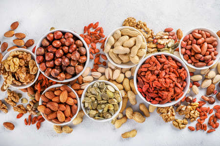 Mixed nuts in small white ceramic bowls on white background. Top view.