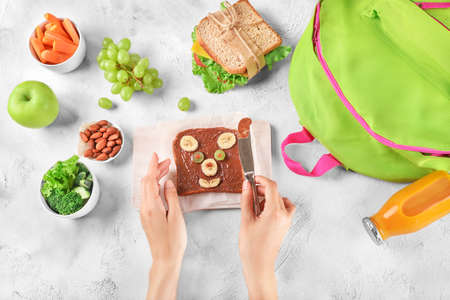 Mum's hands preparing school lunch for child on white background. Top view.の写真素材