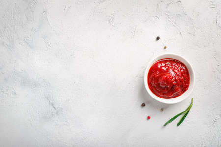 Tomato sauce in small white bowl on white background. Top view. Copy space.の写真素材
