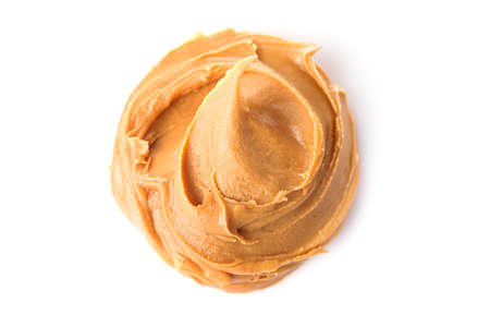 Glass jar and spoon full of crunchy peanut butter with peanuts in nutshell nearby on wooden...