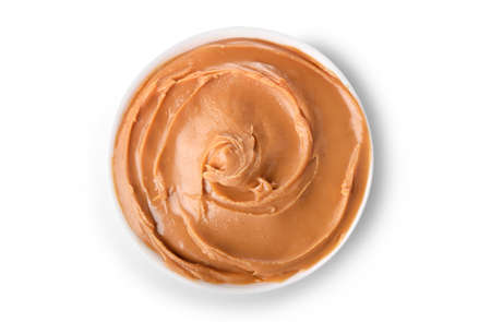 Glass jar and spoon full of crunchy peanut butter with peanuts in nutshell nearby on wooden background. Copy space.の写真素材