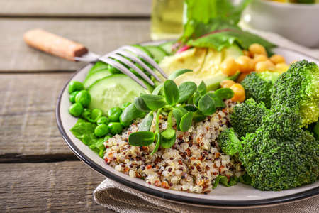 Healthy vegetarian food concept: quinoa with vegetables, seeds and herbs on wooden background.の写真素材