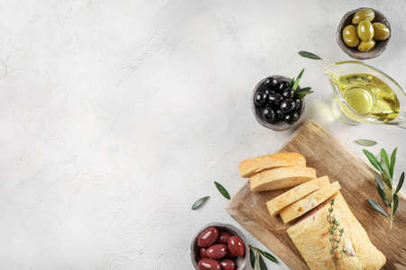 Virgin olive oil, olives and fresh bread on the table. Top view