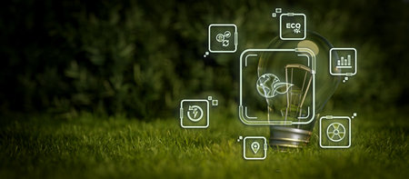 Green energy concept illustrated by a lightbulb on grass with iconsの写真素材