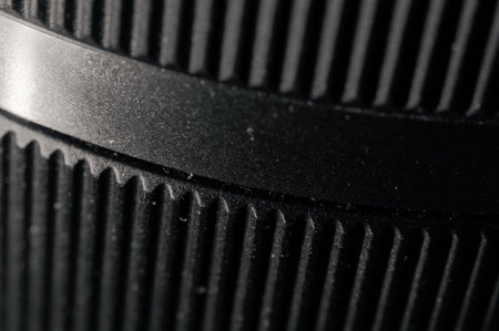Macro closeup selective focus of a ridged black camera lens barrel's extreme detail, showcasing fine...