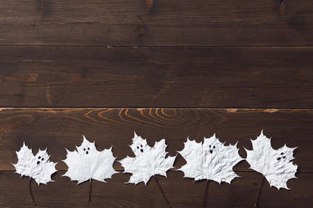 Paper ghosts looks like marle leaf on a dark wood. Flatlay. Copy space.の写真素材