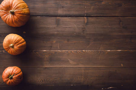 Three pumpkins on a brown wood. Copy space.